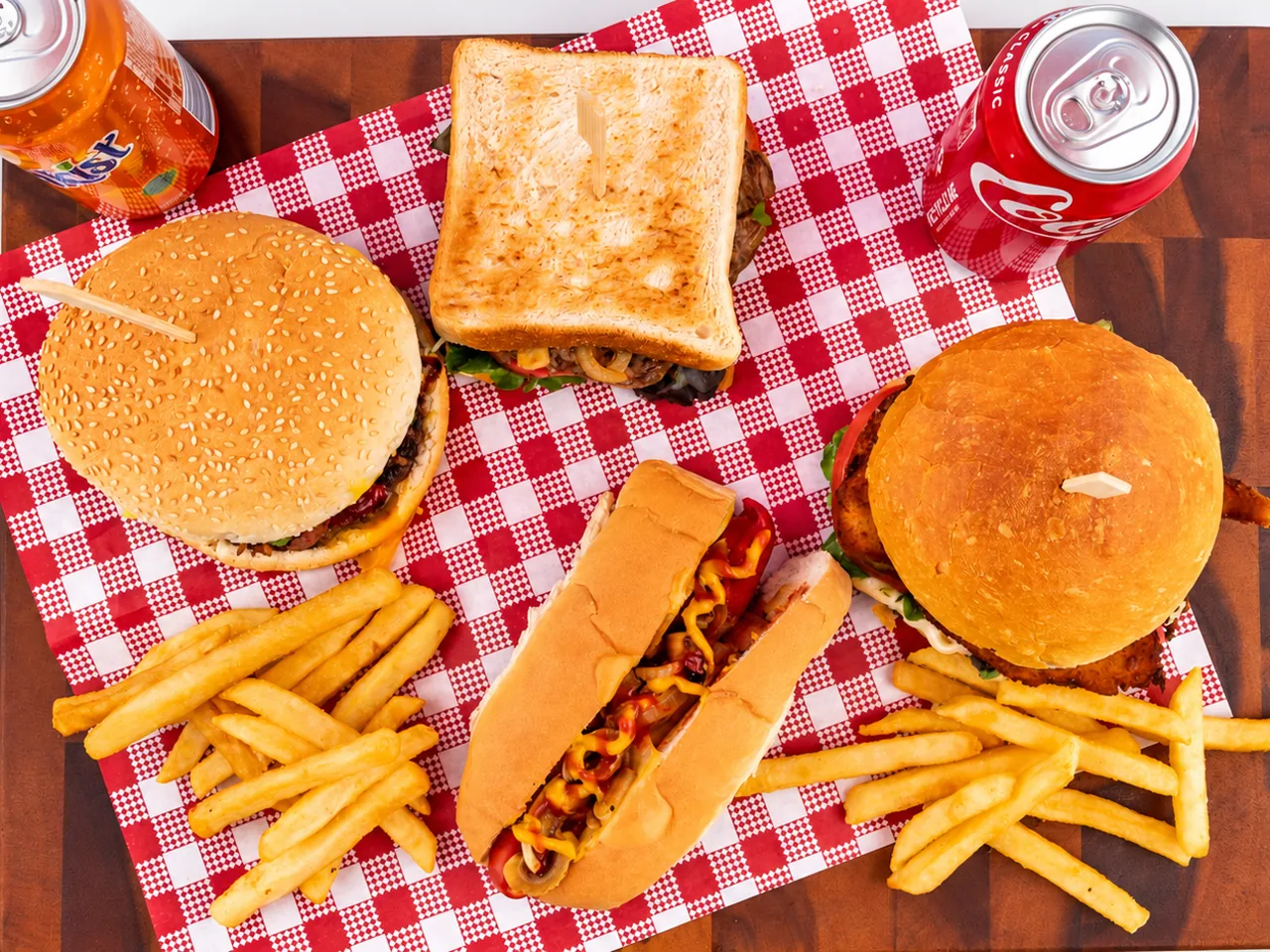 Take It To Go group catering spread with burgers, a toasted sandwich, a hot dog, chips and drinks
